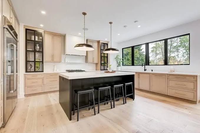 Kitchen with a black island and light oak cabinetry